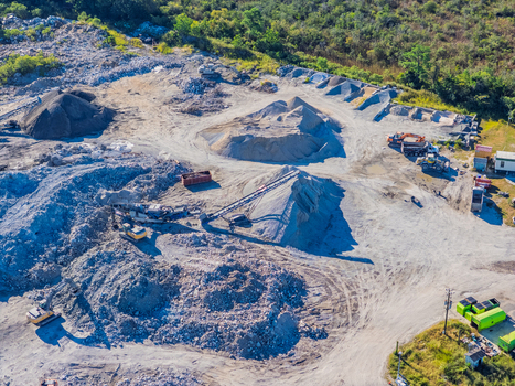 Aerial view of a quarry site featuring large piles of gravel heavy machinery including excavators and a conveyor belt and surrounding vegetation in Wilmington North Carolina United States.