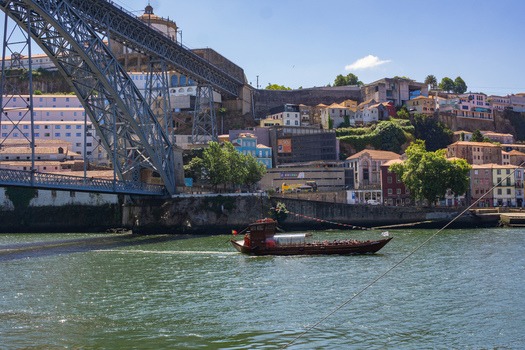 Aerial view of the Dom Luís I Bridge casting shadows on the Douro River as a traditional Rabelo boat glides through the water Porto Porto District Portugal. Aerial view of the Dom Luís I Bridge casting shadows on the Douro River as a traditional Rabelo boat glides through the water Porto Porto District Portugal.