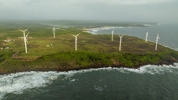 Aerial view of Devgad Windmills situated on a green coastal cliff overlooking the Arabian Sea with waves crashing against the rocky shore in Devgad Maharashtra India. Aerial view of Devgad Windmills situated on a green coastal cliff overlooking the Arabian Sea with waves crashing against the rocky shore in Devgad Maharashtra India.