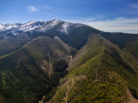 Aerial view of the lush green slopes and snow capped peaks of the Low Tatras mountains under a clear blue sky in Demanovska Dolina Zilina Region Slovakia. Aerial view of the lush green slopes and snow capped peaks of the Low Tatras mountains under a clear blue sky in Demanovska Dolina Zilina Region Slovakia.