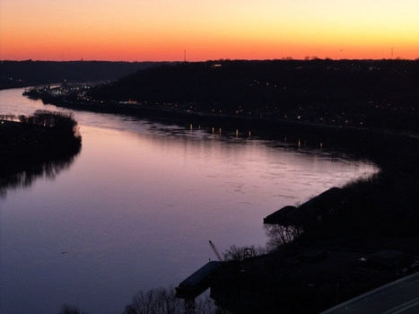Aerial view of the river reflecting the colorful sky at sunset with dark silhouettes of trees and buildings along the riverbanks Cincinnati Ohio United States. Aerial view of the river reflecting the colorful sky at sunset with dark silhouettes of trees and buildings along the riverbanks Cincinnati Ohio United States.