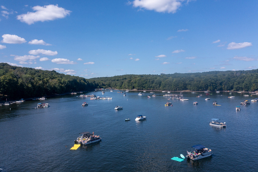 Aerial view of Lake Wallenpaupack with numerous pontoon boats and recreational vessels on calm water surrounded by lush forests in Tannersville Pennsylvania United States.