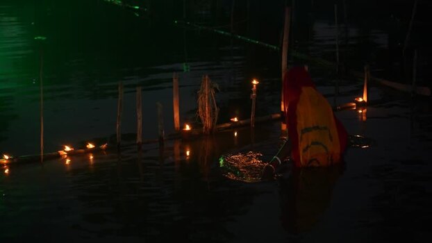 View of a woman performing a ritual with lamps in the water Bangladesh. View of a woman performing a ritual with lamps in the water Bangladesh.
