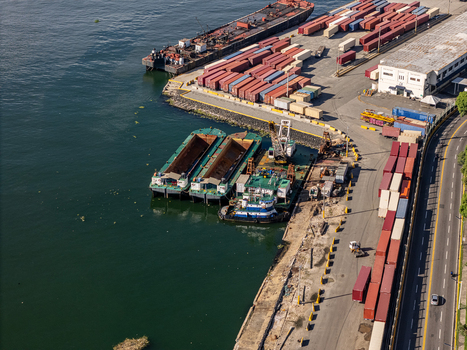 Aerial view of the Rio Ozama port area featuring cargo ships numerous shipping containers and tugboats docked along the industrial waterfront in Santo Domingo Santo Domingo Dominican Republic.