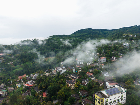 Aerial view of hillside houses nestled among lush tropical vegetation and misty clouds in Kandy Central Province Sri Lanka. Aerial view of hillside houses nestled among lush tropical vegetation and misty clouds in Kandy Central Province Sri Lanka.