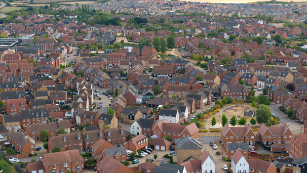 Aerial view of a modern residential housing estate with rows of brick houses winding streets and green spaces in Bedford England United Kingdom. Aerial view of a modern residential housing estate with rows of brick houses winding streets and green spaces in Bedford England United Kingdom.