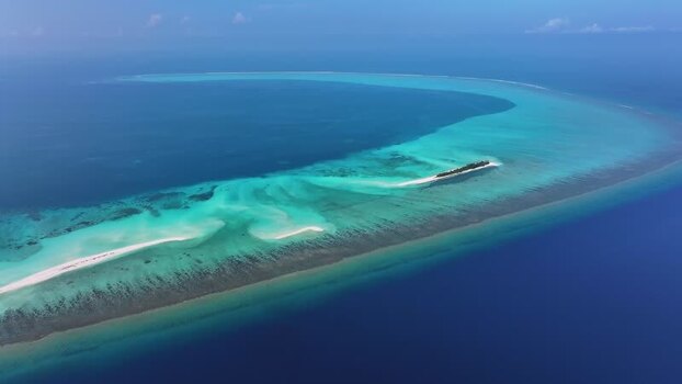 Aerial view of a tropical island and coral reef in Maldives.