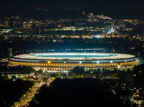 Aerial view of the illuminated Olympiastadion Berlin at night surrounded by the glowing city lights of Berlin Berlin Germany.
