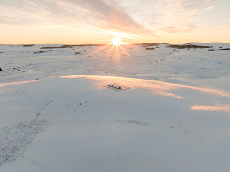 Aerial view of a sun kissed snow covered landscape where the white expanse meets the warm glow of the setting sun creating a serene winter scene Nasbinals Occitanie France.
