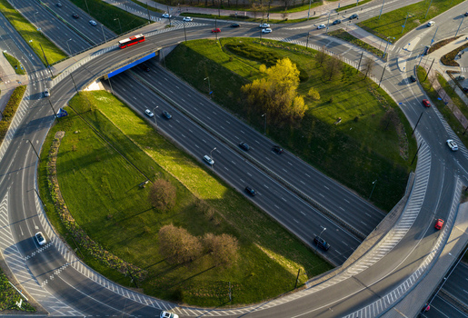 Aerial view of a multi level highway interchange with traffic and a red bus driving on asphalt roads surrounded by green grass and trees in Vilnius County Lithuania. Aerial view of a multi level highway interchange with traffic and a red bus driving on asphalt roads surrounded by green grass and trees in Vilnius County Lithuania.