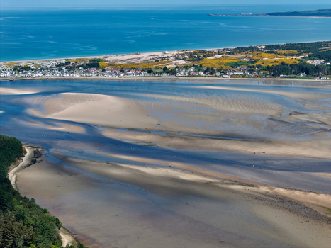 Aerial view of Findhorn Bay featuring intricate sandbars the coastal village and the blue waters of the Moray Firth in Findhorn Scotland United Kingdom. Aerial view of Findhorn Bay featuring intricate sandbars the coastal village and the blue waters of the Moray Firth in Findhorn Scotland United Kingdom.