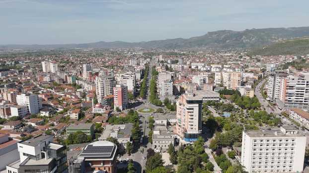 Aerial view of the city of Elbasan featuring a central roundabout dense urban architecture and surrounding mountains under a clear sky in Elbasan Elbasan County Albania.