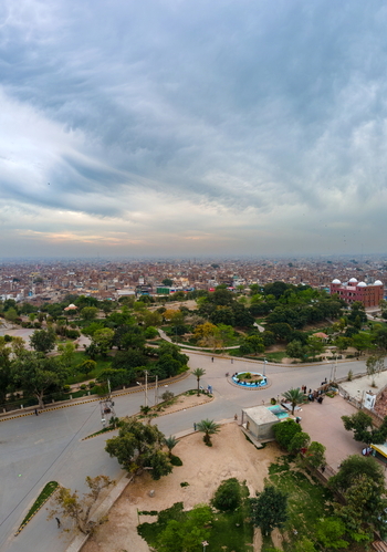 Aerial view of Shah Rukn E Alam Town featuring lush green parkland winding pathways a roundabout and the sprawling urban skyline of Multan Punjab Pakistan.