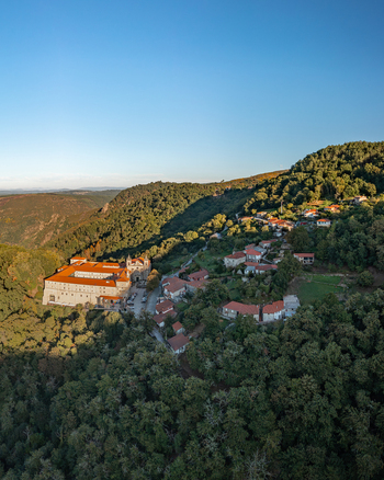 Aerial view of Monastery of Santo Estevo de Ribas de Sil in Ribeira Sacra featuring historic stone architecture surrounded by lush forests and a village in O Covelo Ourense Spain.