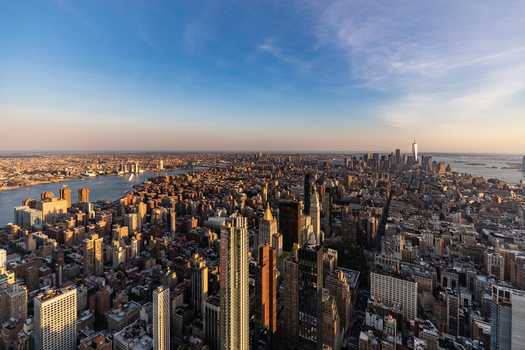 New York United States 09 August 2021 Aerial view of the New York City skyline at sunset featuring dense urban architecture skyscrapers and the East River under a clear blue sky.