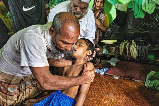 Banshkhali Upazila Chittagong Division Bangladesh 10 July 2026 View of a grieving man holding an unconscious child in a room surrounded by distressed family members. Banshkhali Upazila Chittagong Division Bangladesh 10 July 2026 View of a grieving man holding an unconscious child in a room surrounded by distressed family members.
