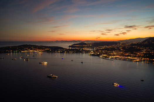 Aerial view of the coastline of Eze at sunset featuring illuminated yachts and boats on the water with the town lights glowing along the shore in Eze Provence Alpes Cote d Azur France. Aerial view of the coastline of Eze at sunset featuring illuminated yachts and boats on the water with the town lights glowing along the shore in Eze Provence Alpes Cote d Azur France.