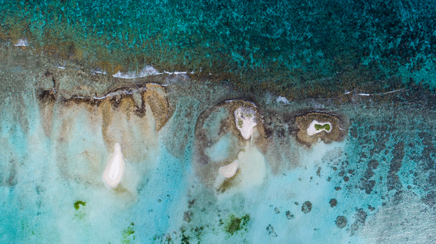 Aerial view of the Los Roques archipelago featuring small sandy cays surrounded by vibrant turquoise coral reefs and clear Caribbean waters in Los Roques Dependencias Federale Venezuela. Aerial view of the Los Roques archipelago featuring small sandy cays surrounded by vibrant turquoise coral reefs and clear Caribbean waters in Los Roques Dependencias Federale Venezuela.
