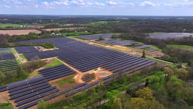 Aerial view of a large solar farm surrounded by green forests United States. Aerial view of a large solar farm surrounded by green forests United States.