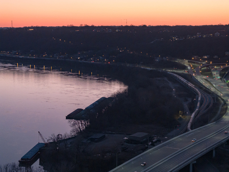 Aerial view of the river reflecting the colors of the sunset with bridges and roads winding along the dark shoreline Cincinnati Ohio United States. Aerial view of the river reflecting the colors of the sunset with bridges and roads winding along the dark shoreline Cincinnati Ohio United States.