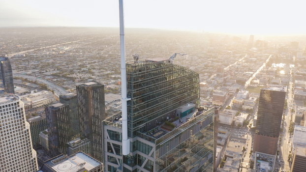 Aerial view of the Wilshire Grand Center skyscraper with its prominent spire and rooftop terrace overlooking the dense urban cityscape of Los Angeles California United States.