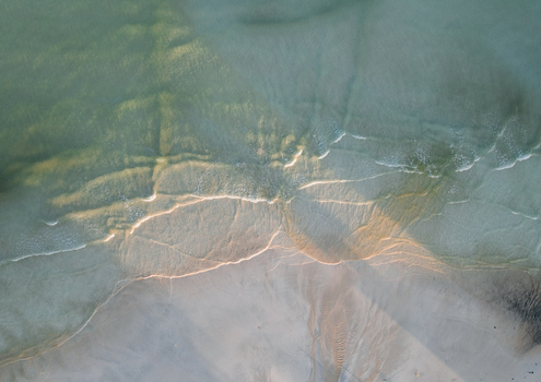 Aerial view of the mesmerizing dance of sunlight on gentle waves meeting the shore creating a symphony of blues and sandy whites Pantai Tanjung Aan West Nusa Tenggara Indonesia. Aerial view of the mesmerizing dance of sunlight on gentle waves meeting the shore creating a symphony of blues and sandy whites Pantai Tanjung Aan West Nusa Tenggara Indonesia.