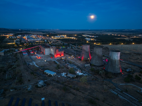 Aerial view of the former thermal power plant in Inota Hungary with illuminated cooling towers industrial buildings and a moon over the site on a late summer evening.