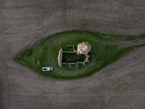 Aerial view of Pusztatorony ruins surrounded by a green grassy patch in the middle of a plowed field with a small white vehicle parked nearby in Somogyvamos Hungary. Aerial view of Pusztatorony ruins surrounded by a green grassy patch in the middle of a plowed field with a small white vehicle parked nearby in Somogyvamos Hungary.