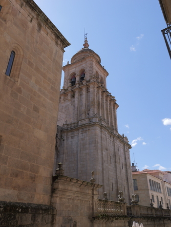 View of the historic stone bell tower of the Catedral de Ourense rising against a clear blue sky featuring intricate architectural details in Ourense Ourense Spain. View of the historic stone bell tower of the Catedral de Ourense rising against a clear blue sky featuring intricate architectural details in Ourense Ourense Spain.