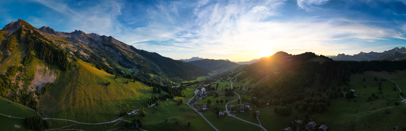 Aerial view of sun kissed alpine meadows and forests embrace the quaint village nestled in the valley La Clusaz Auvergne Rhône Alpes France. Aerial view of sun kissed alpine meadows and forests embrace the quaint village nestled in the valley La Clusaz Auvergne Rhône Alpes France.