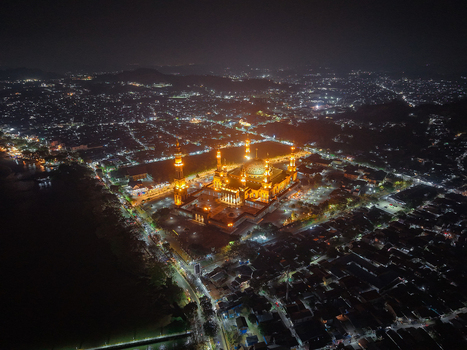 Aerial view of Baitul Muttaqien Mosque illuminated at night surrounded by the urban landscape of Samarinda East Kalimantan Indonesia.