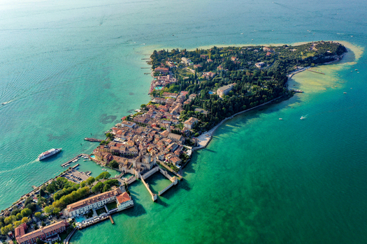 Aerial view of Castello Scaligero di Sirmione and the historic peninsula surrounded by the turquoise waters of Lake Garda in Sirmione Lombardia Italy.
