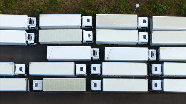 Aerial view of a logistics hub with rows of white semi trailer trucks parked in an industrial yard in Bedford England United Kingdom. Aerial view of a logistics hub with rows of white semi trailer trucks parked in an industrial yard in Bedford England United Kingdom.
