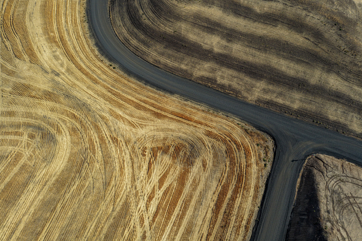 Aerial view of the rolling hills and harvested fields with intricate tractor tracks and a winding dirt road in the Palouse region of Palouse Washington United States. Aerial view of the rolling hills and harvested fields with intricate tractor tracks and a winding dirt road in the Palouse region of Palouse Washington United States.