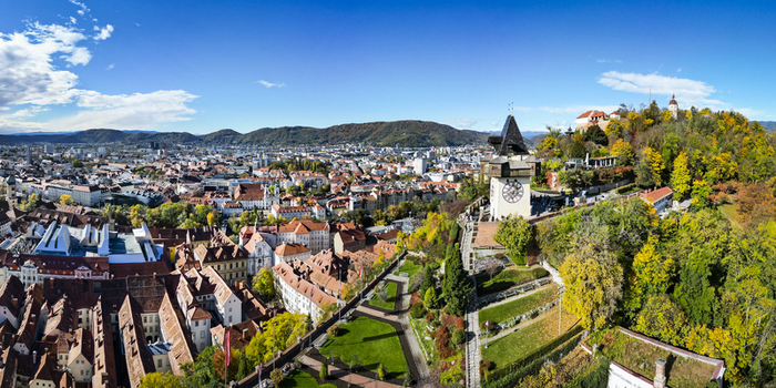 Aerial view of the iconic clock tower the Schlossberg hill and the cityscape under a vast blue sky Graz Styria Austria.