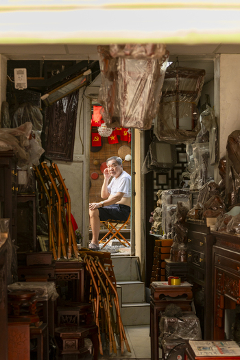Hanoi Ha Noi Vietnam 11 November 2025 View of an elderly man sitting on a chair inside a traditional shop filled with wooden furniture and crafts in the historic streets of Hanoi.
