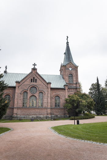 View of the historic red brick Jyvaskyla City Church with its tall steeple arched windows and surrounding green lawn in Jyvaskyla Central Finland Finland.