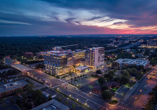 Reston Virginia United States 27 May 2020 Aerial view of modern office buildings and residential complexes illuminated at dusk under a vibrant sunset sky. Reston Virginia United States 27 May 2020 Aerial view of modern office buildings and residential complexes illuminated at dusk under a vibrant sunset sky.