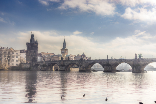 View of the historic Charles Bridge and the Old Town Bridge Tower over the Vltava River under a cloudy sky in Prague Prague Czechia. View of the historic Charles Bridge and the Old Town Bridge Tower over the Vltava River under a cloudy sky in Prague Prague Czechia.