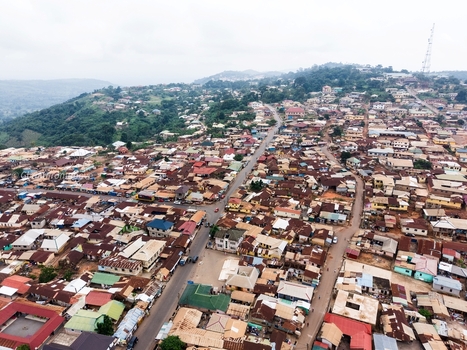 Aerial view of dense residential housing with metal roofs winding roads and hilly terrain in Ghana. Aerial view of dense residential housing with metal roofs winding roads and hilly terrain in Ghana.