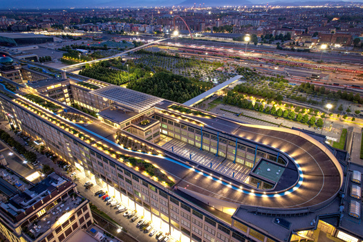 Aerial view of the historic Lingotto building featuring the iconic rooftop test track illuminated at twilight in Turin Piedmont Italy. Aerial view of the historic Lingotto building featuring the iconic rooftop test track illuminated at twilight in Turin Piedmont Italy.