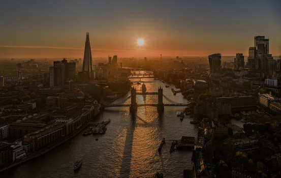 Aerial view of Tower Bridge and The Shard at sunset with the River Thames flowing through the city skyline under a golden sky in London Greater London United Kingdom. Aerial view of Tower Bridge and The Shard at sunset with the River Thames flowing through the city skyline under a golden sky in London Greater London United Kingdom.