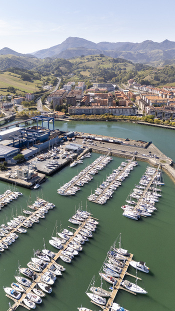 Aerial view of the marina in Zumaia featuring rows of sailboats docked in the harbor with the town and mountains in the background in Zumaia Basque Country Spain.