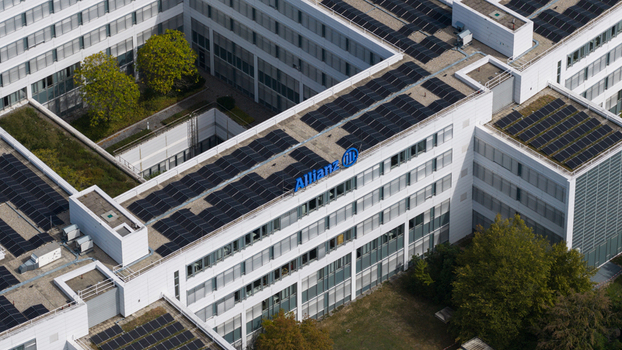 Unterfohring Germany 12 September 2026 Aerial view of the Allianz Commercial headquarters building featuring a modern white facade solar panels on the roof and surrounding green trees.