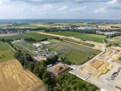 Aerial view of Neufinsing electrical substation with transformers power lines and switchyard equipment surrounded by agricultural fields and construction areas in Finsing Bayern Germany.