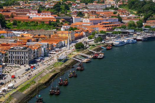 Aerial view of the Douro River reflecting the sky lined with historic buildings and boats contrasting the terracotta rooftops with the deep blues Porto Porto District Portugal. Aerial view of the Douro River reflecting the sky lined with historic buildings and boats contrasting the terracotta rooftops with the deep blues Porto Porto District Portugal.