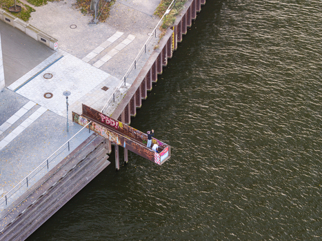 Aerial view of the Molecule Men sculpture situated on the Spree river with people standing on a metal platform along the embankment in Berlin Berlin Germany. Aerial view of the Molecule Men sculpture situated on the Spree river with people standing on a metal platform along the embankment in Berlin Berlin Germany.