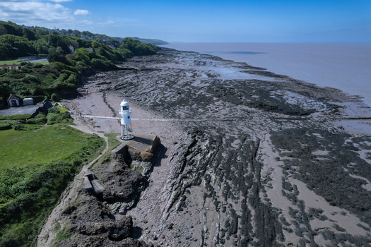 Aerial view of Black Nore Lighthouse standing on the rocky coastline with tidal mudflats and green cliffs in Portishead England United Kingdom. Aerial view of Black Nore Lighthouse standing on the rocky coastline with tidal mudflats and green cliffs in Portishead England United Kingdom.