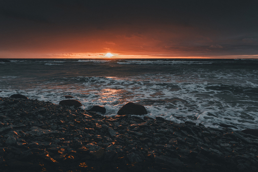 View of the rocky Saxby coast at sunset with dark clouds and waves crashing on the shore in Saxby Laane maakond Estonia.