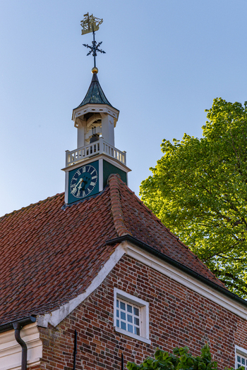 View of the historic Greetsiel church clock tower featuring a ship weather vane and red brick architecture against a clear blue sky in Krummhorn Lower Saxony Germany. View of the historic Greetsiel church clock tower featuring a ship weather vane and red brick architecture against a clear blue sky in Krummhorn Lower Saxony Germany.
